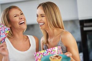 bonitas dos chicas adultas en la casa con pastel de cumpleaños foto