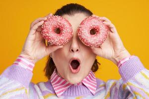 Young beautiful woman over yellow background with donuts photo