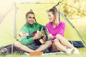 Couple camping in forest and playing guitar photo