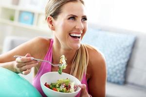 mujer joven comiendo ensalada saludable después del entrenamiento foto