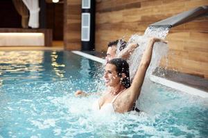 pareja feliz relajándose en el spa de la piscina foto