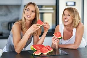 Nice two adult girls in the kitchen with watermelon photo