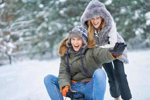 Couple having fun with sledge on snow in winter photo