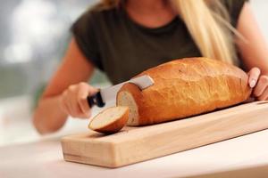 Woman slicing loaf of bread photo