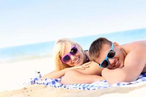 Joyful couple sunbathing at the beach photo