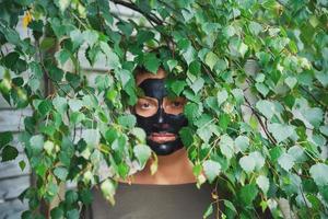 mujer joven en la naturaleza con máscara negra en la cara foto
