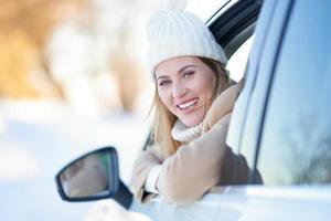 mujer feliz conduciendo un coche en invierno cubierto de nieve foto