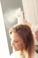 Hairdresser using hair spray photo