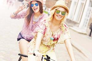 Two girl friends riding tandem bicycle photo