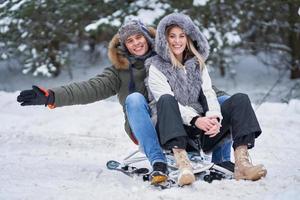 Couple having fun with sledge on snow in winter photo