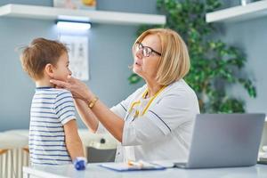 Pediatrician doctor examining little kids in clinic photo