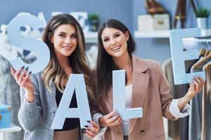 Two girls on shopping holding sale percentage sign. photo