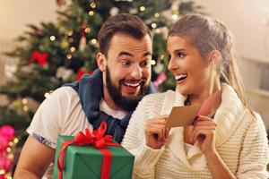 Young couple with present over Christmas tree photo