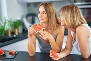 Nice two adult girls in the kitchen with watermelon photo