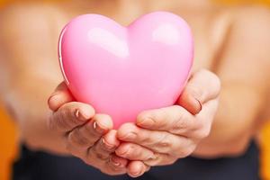 Young nice woman holding heart isolated over yellow background photo