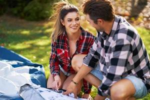 Young nice couple having fun on camping setting up tent photo