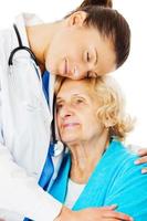 Doctor Embracing Senior Woman Over White Background photo