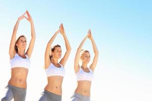 grupo de mujeres practicando yoga en la playa foto