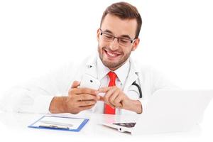 Doctor with laptop smartphone and documents photo