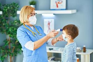 médico pediatra que examina a los niños pequeños en el control de temperatura de la clínica foto