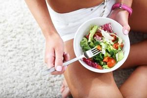 mujer joven comiendo ensalada saludable después del entrenamiento foto