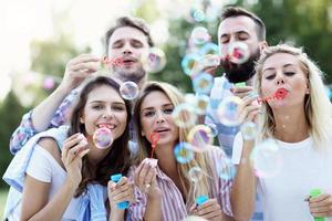 Happy group of friends blowing bubbles outdoors photo