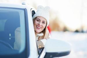 mujer feliz conduciendo un coche en invierno cubierto de nieve foto