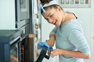 mujer joven limpiando el horno en la cocina foto