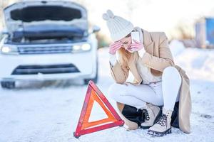 mujer joven que tiene problemas con el coche en invierno foto