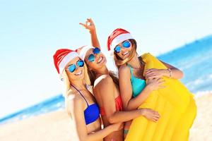 grupo de chicas con sombreros de santa divirtiéndose en la playa foto