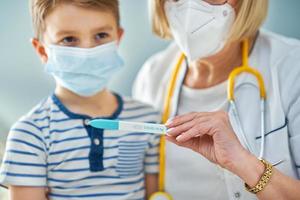 Pediatrician doctor examining little kids in clinic covid test photo