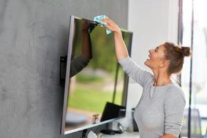 Picture of young woman cleaning tv screen photo