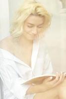 mujer bonita joven leyendo un libro en la ventana foto