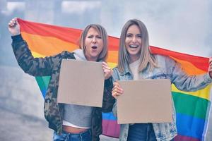 pareja lgbt con tablero de mensajes en blanco y bandera foto