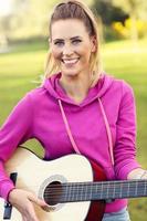 Happy woman playing guitar outdoors photo