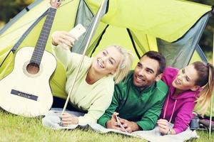 Group of friends camping in forest and taking selfie photo