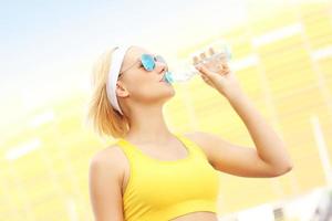 Woman drinking water in front of Amber Stadium photo