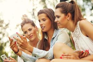 Group of girlfriends using smartphone outdoors photo