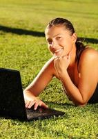 Pretty young girl working on her laptop on the grass photo