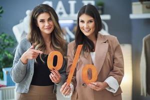 Two girls on shopping holding sale percentage sign. photo