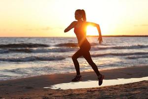 Woman running alone at beautiful dusk on the beach photo