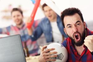 Happy male friends cheering and watching sports on tv photo