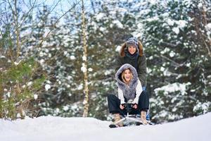 Couple having fun with sledge on snow in winter photo