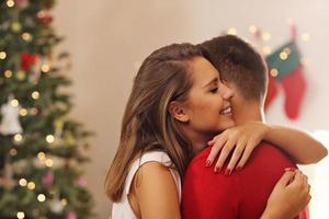 Young couple hugging over Christmas tree photo