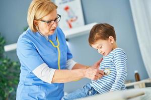 Pediatrician doctor examining little kids in clinic photo