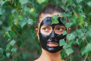 Young woman in nature with black mask on face photo