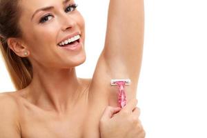 Adult woman shaving armpit with pink shaver isolated on white background photo