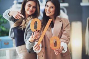 Two girls on shopping holding sale percentage sign. photo