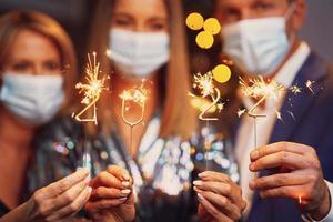 Beautiful young friends in masks having fun at New Year's Eve Party 2022 photo