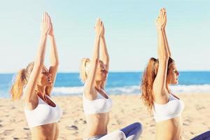 Group of women practising yoga on the beach photo